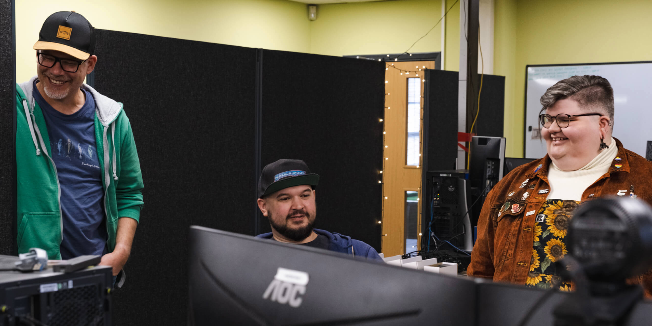 Photo of three Stainless Games team members in the office